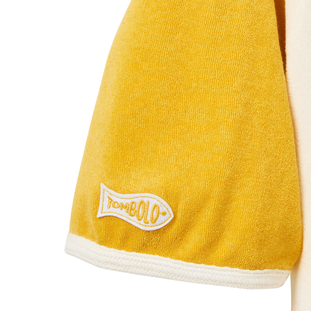 Yellow towel with a white border and 'Tombolo' logo on a white background